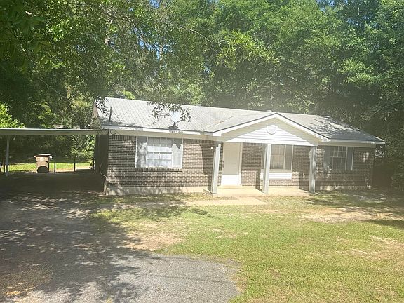 Front view with covered carport that leads to the fenced backyard.