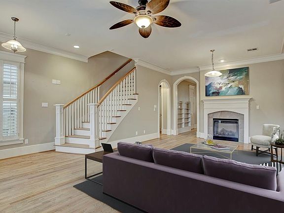 First floor living room has hardwood floors, decorative crown moulding, and a unique two-sided fireplace. Closet and half bathroom are through the arch to the left. Picture is virtually staged.