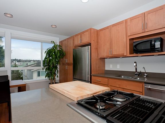 Silestone and stainless, gas cooktop, undermount sink, recessed lighting and a wall of windows compl