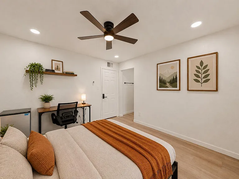 Well-appointed bedroom with a ceiling fan, dedicated desk workspace, and mini fridge for added convenience.