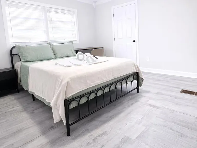 Spacious bedroom with a comfortable bed, ceiling fan, and wide windows with blinds for light and privacy.