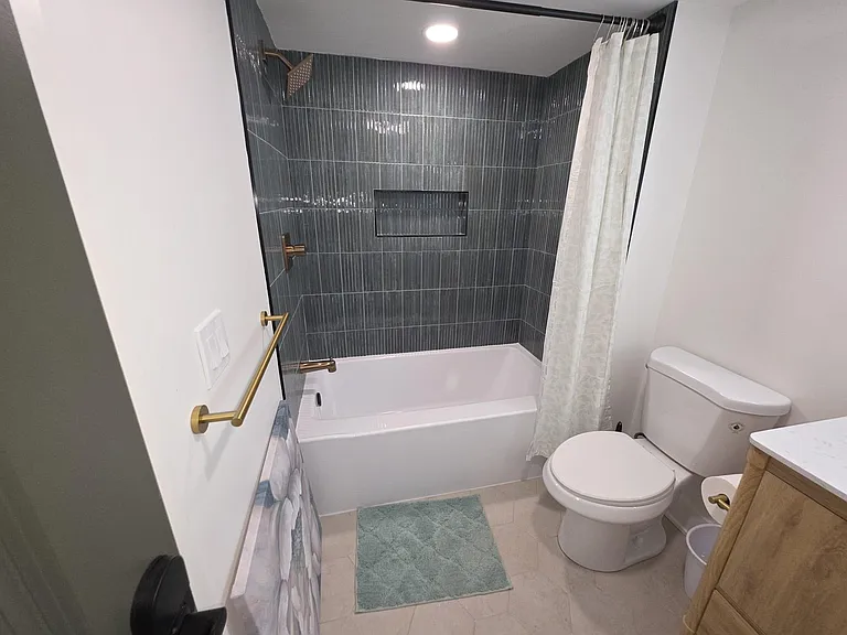 Updated full bath with tiled tub/shower surround, built-in niche storage, and modern fixtures with vanity space.