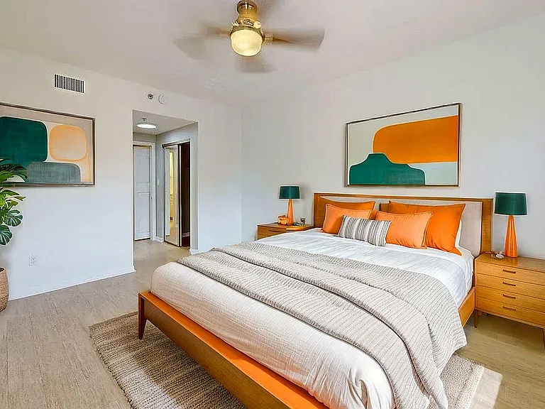 Bright, modern bedroom with vibrant orange accents, mid-century furniture, and stylish artwork.