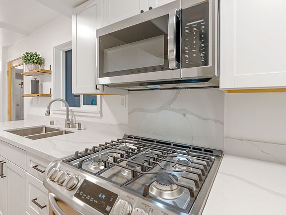 Kitchen - quartz counters, newer cabinets, 5 burner stove, microwave hood, 2 windows and deck access.