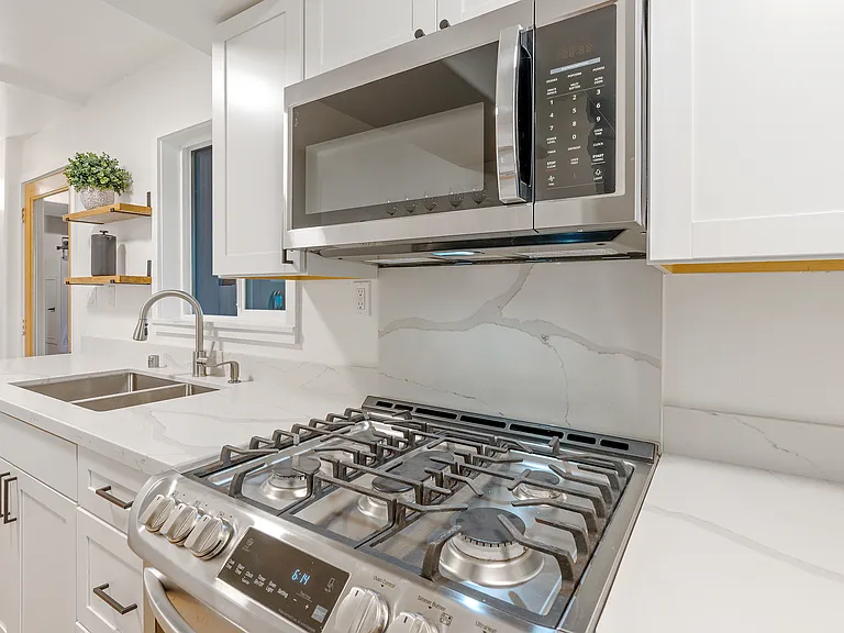 Kitchen - quartz counters, newer cabinets, 5 burner stove, microwave hood, 2 windows and deck access.