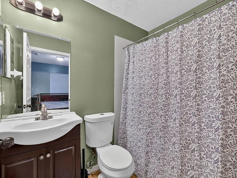 Full bathroom with single-sink vanity, mirror storage, and a tub/shower combo with curtain for everyday convenience.