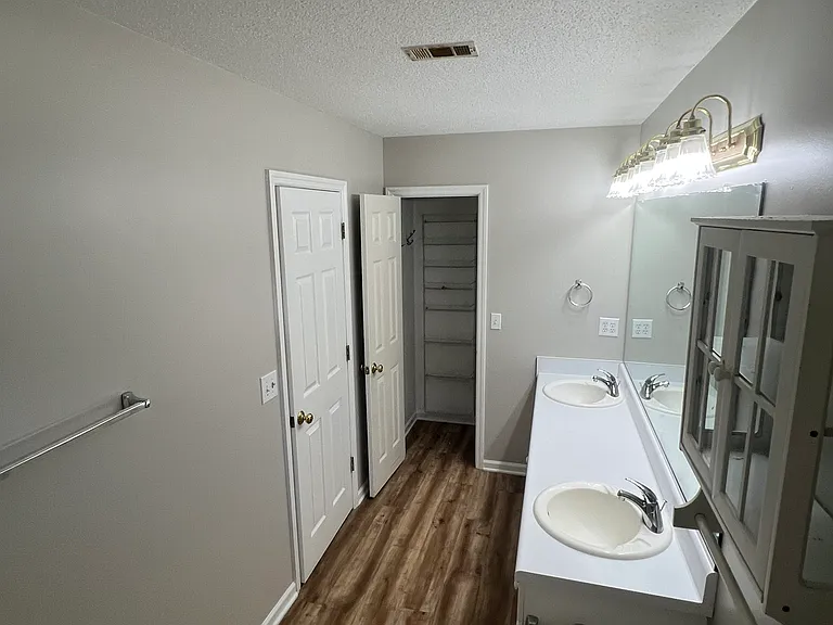 Master bathroom with two sinks, full tub/shower and linen/storage closet
