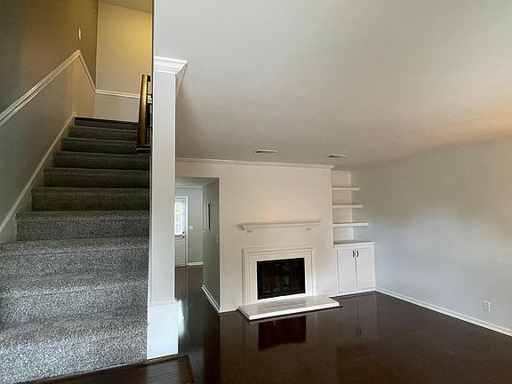 Living Room with wood burning fireplace and shelving. Stairs to upstairs bedrooms.