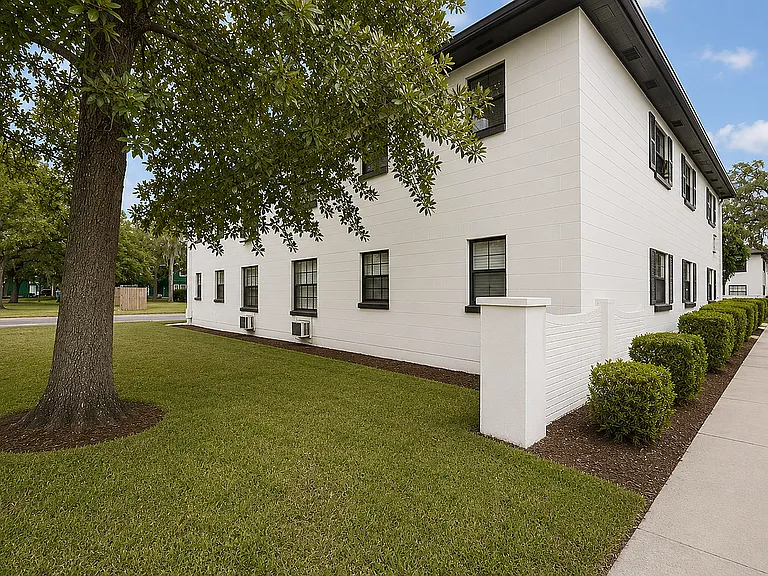 Charming apartment building with a lush green lawn and elegant white exterior, perfect for a serene living experience.