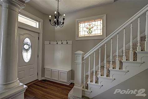 The foyer offers plenty of space with ornate details such as hall tree/bench, stain glass window, decorative columns set on half wall with wainscoting and articulate wood work leading up the steps.