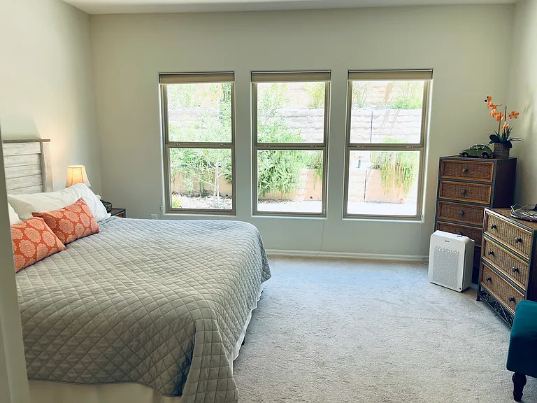 Primary bedroom with king size bed, and windows out to walled backyard.