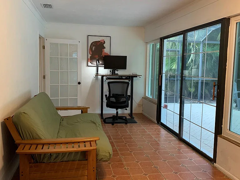 The Florida room with a futon that can be easily turned into a full-size bed, a fully equipped height adjustable office desk with a chair and an anti-fatigue floor mat and a double sliding door to the deck.