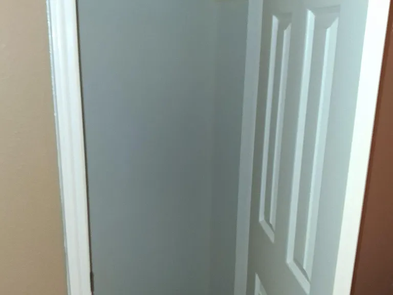 Empty closet or storage nook with hanging rod and shelf, offering convenient space to keep clothing and essentials organized.