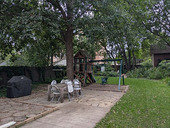 Large fenced in yard with playset and fire pit