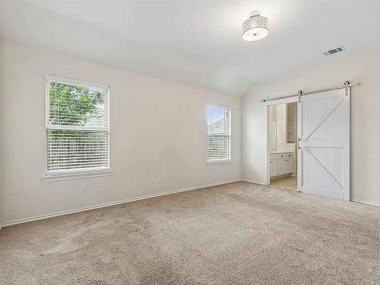 Carpeted interior room with light-colored walls and a vaulted ceiling
