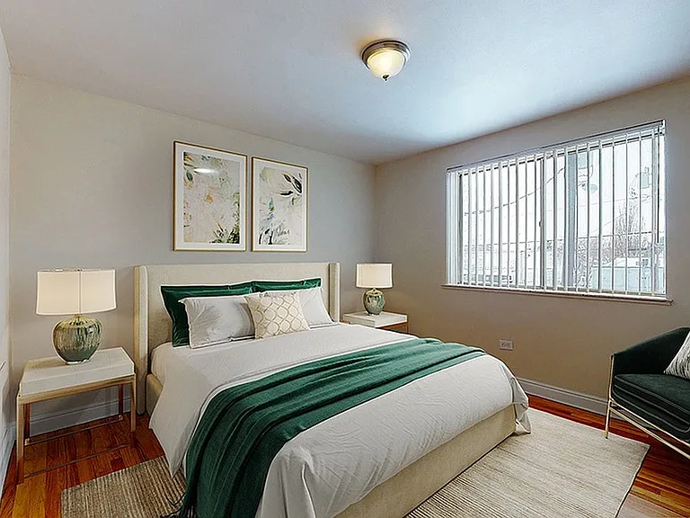 Inviting bedroom with elegant decor, highlighting a plush bed with a green throw and stylish bedside lamps, complemented by large windows for ample natural light.