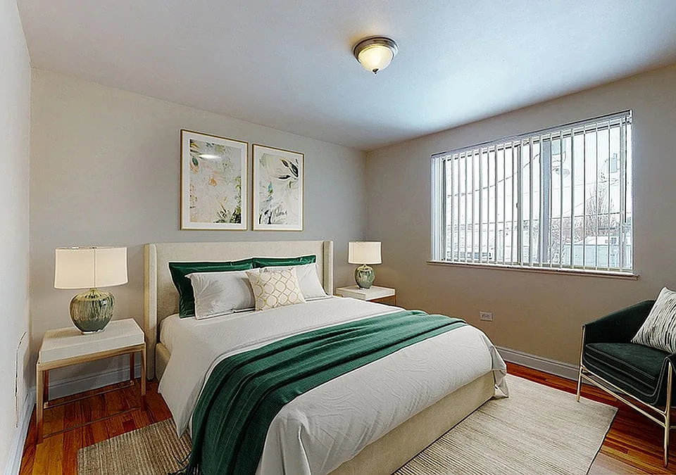 Inviting bedroom with elegant decor, highlighting a plush bed with a green throw and stylish bedside lamps, complemented by large windows for ample natural light.