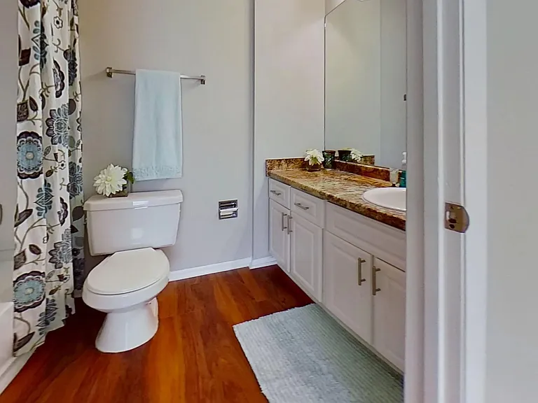 The Martinique Autograph floor plan offers a beautifully designed bathroom featuring a granite-style countertop, modern cabinetry, and hardwood-style flooring.