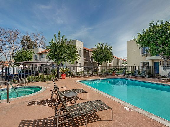 Swimming pool and spa surrounded by lounge chairs.