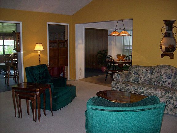  Spacious living room view from entry with cathedral ceiling and ceiling fan.  Opens to dining and den areas.