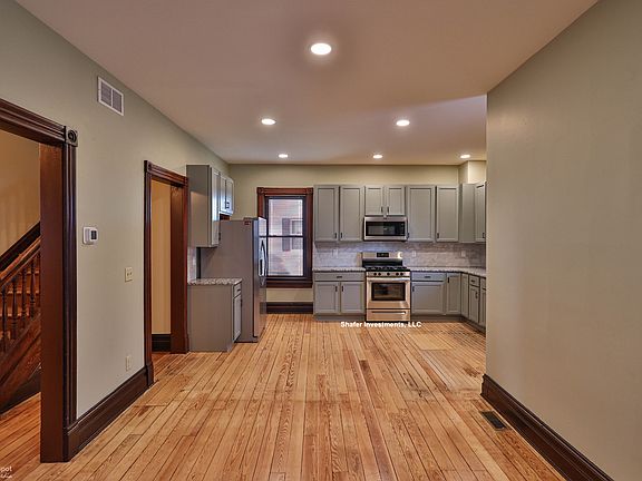 The photo showcases the new cabinets, appliances, lighting, and refinished floors.
