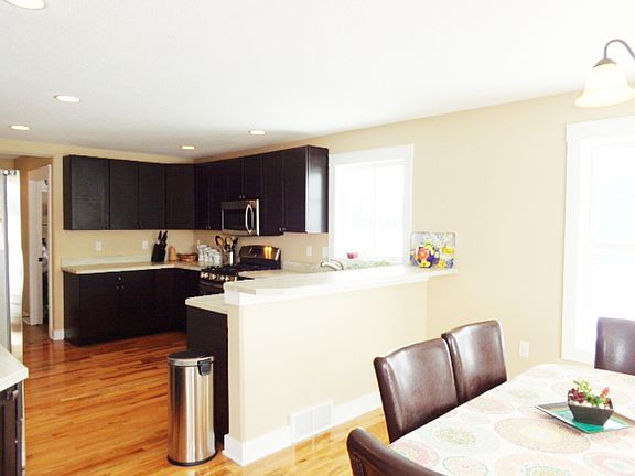 Kitchen open to dining area also has wood flooring.
