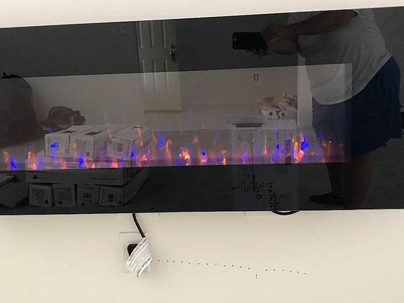 Floating fireplace in the living room with white stone wall from floor to ceiling.