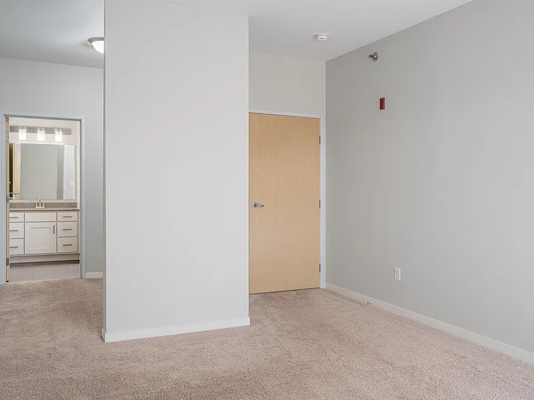 Bright, modern bedroom with plush carpet leading to an en-suite bathroom, showcasing a contemporary vanity. Bright, modern bedroom with plush carpet leading to an en-suite bathroom, showcasing a contemporary vanity.