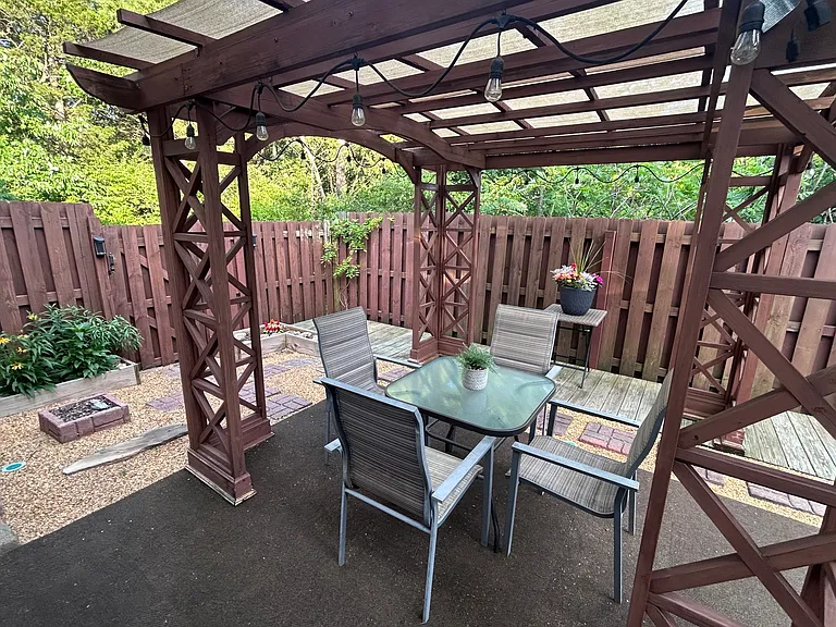 Fenced in back patio with covered seating and plants.