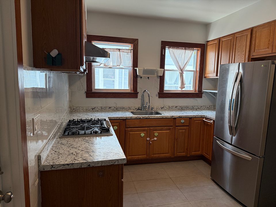 Kitchen with refrigerator, gas stove, and range hood.