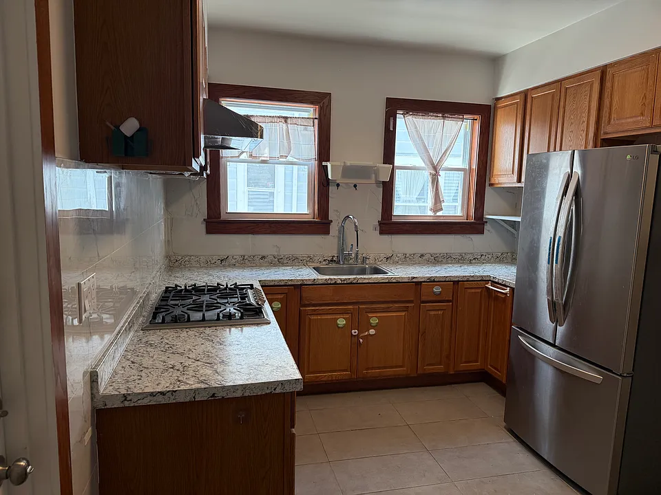 Kitchen with refrigerator, gas stove, and range hood.