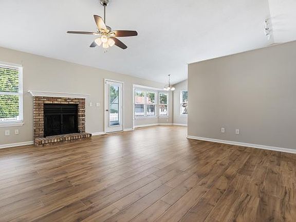 Greatroom features vaulted ceiling, fan, newer luxury vinyl plank flooring and a wood burning fireplace