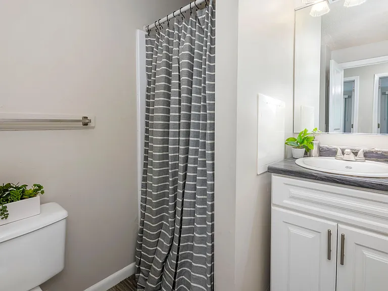 Our modern bathroom showcases black fusion granite-style countertops and a spacious walk-in shower. Your daily sanctuary awaits.