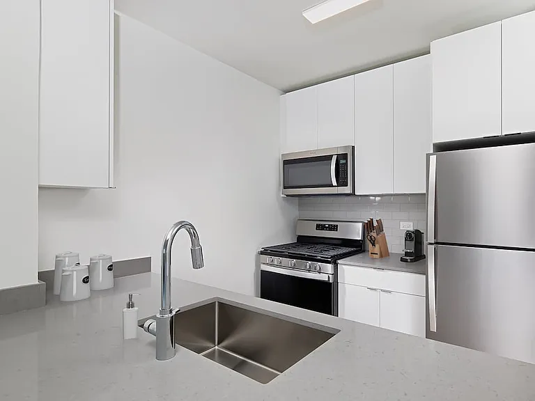 Renovated Package I kitchen with grey quartz countertops, grey subway tile backsplash, stainless steel appliances, and hard surface plank flooring