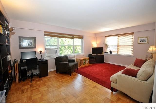 Large living room with parquet floors and two large windows featuring gorgeous tree-topped views of 