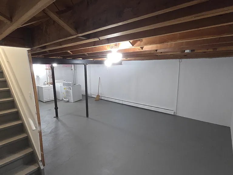 Large, clean lower-level flex space with freshly painted floor and walls.