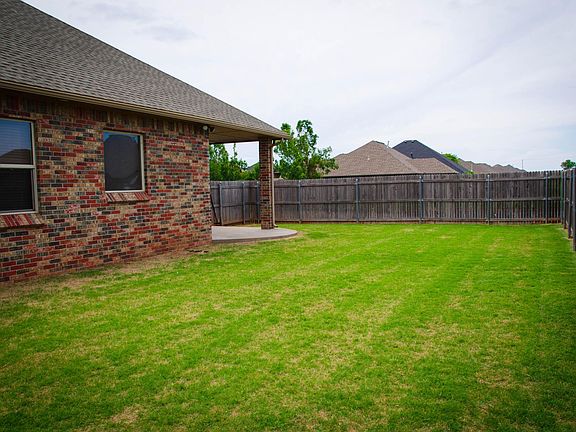 Backyard has a wooden fence protecting the property. Large grassy backyard.