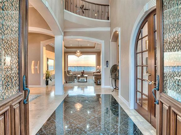 Grand foyer is graced with travertine & granite flooring and soaring ceilings. The spectacular views of the water can be seen throughout this home and are evident upon your first step in. Look at the detailing in those front doors!