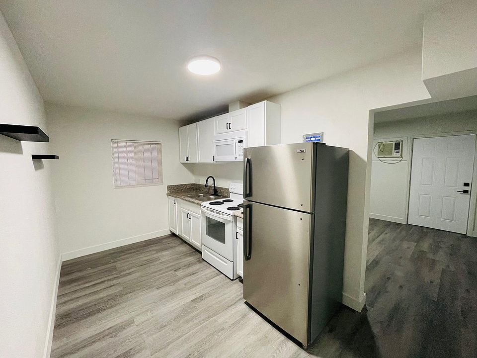 SPACIOUS FULL KITCHEN WITH FLOATING SHELVES AND STAINLESS STEEL FRIDGE