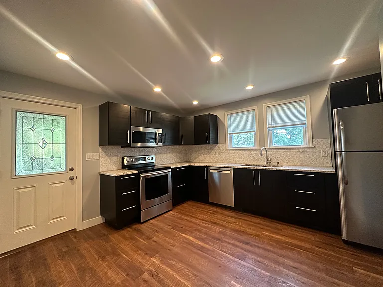 Upgraded kitchen with granite countertops, upgraded cabinetry, and full stainless appliance suite including dishwasher and microwave.