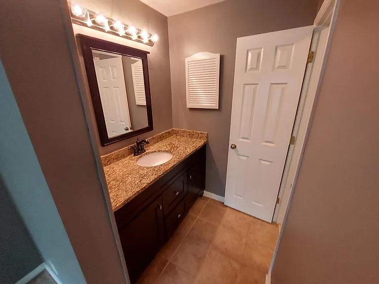 Private primary dressing area with tile floor, great vanity, and mirror.