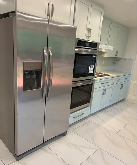 Left side of kitchen with new cabinet doors, fridge, ovens, and stove