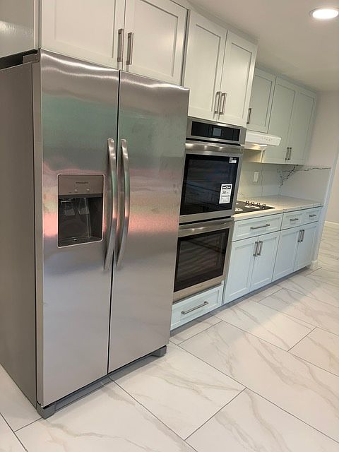 Left side of kitchen with new cabinet doors, fridge, ovens, and stove