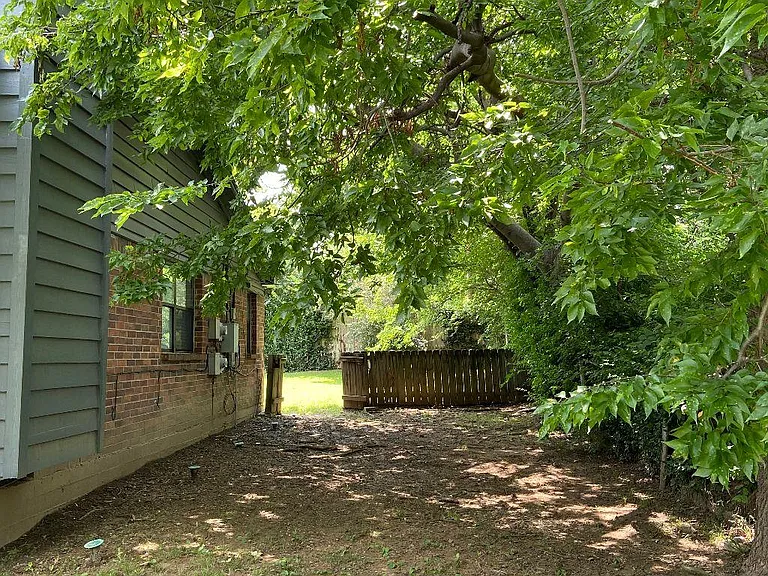Shaded side yard view leading to backyard.