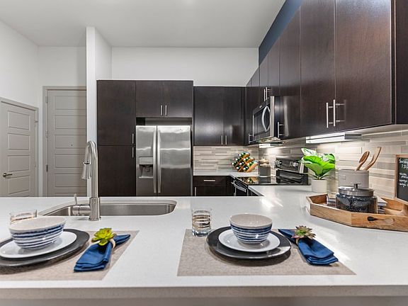Our contemporary kitchens feature under-cabinet lighting and premium quartz countertops with tile backsplash