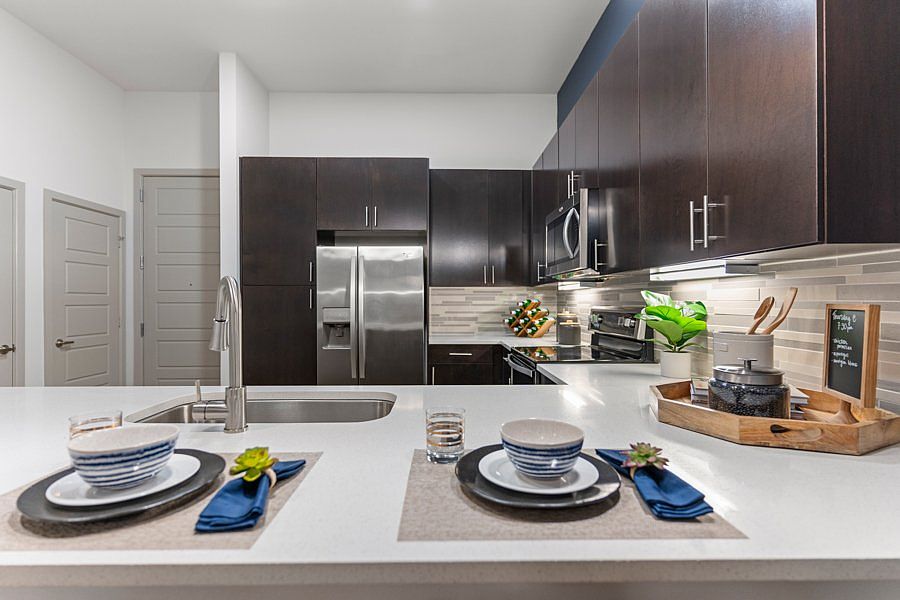 Our contemporary kitchens feature under-cabinet lighting and premium quartz countertops with tile backsplash