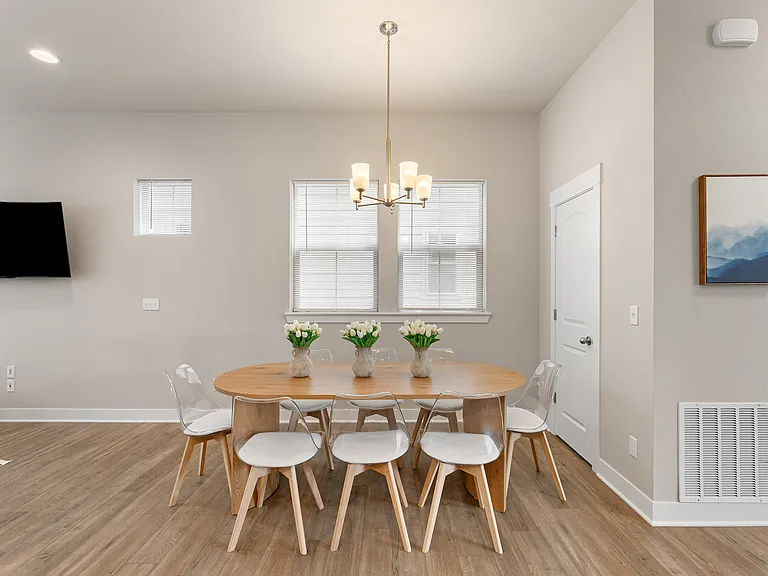Enjoy a bright dining area with a large wooden table and comfortable chairs for six. Natural light fills the space, creating a warm and welcoming atmosphere perfect for meals, gatherings, or working comfortably during your stay.