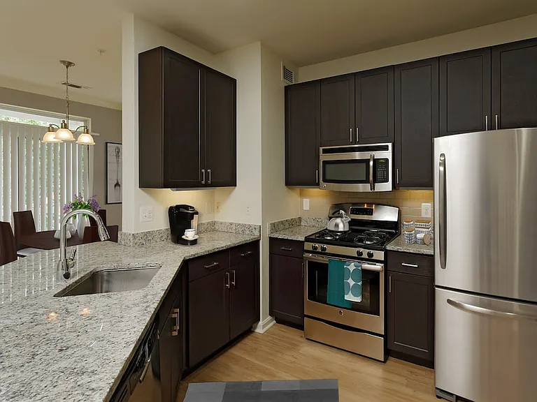 Renovated Package III kitchen with espresso cabinetry, granite countertops, stainless steel appliances, tile backsplash and hard surface flooring