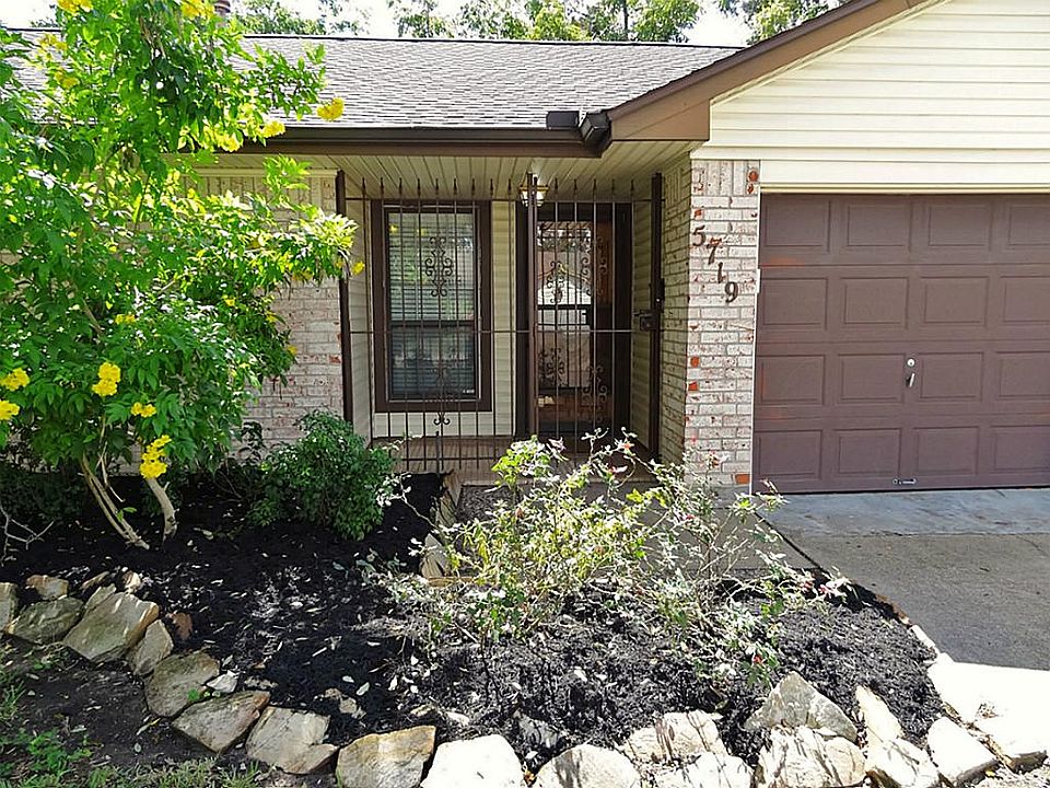 Home has flowerbeds trimmed with flagstone and a gated, covered front porch. Front door has a glass storm door to protect the leaded glass oval front door from the weather. Notice the gutters around the home.