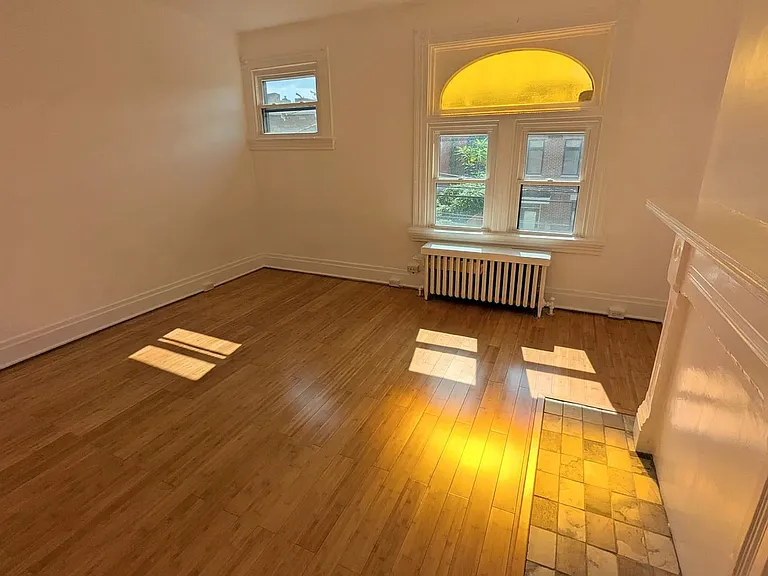 2nd Floor Front Bedroom _ flooded with light, especially beautiful because of the antique stained glass yellow arched transom window, good sized closet and pristine hearth & fireplace